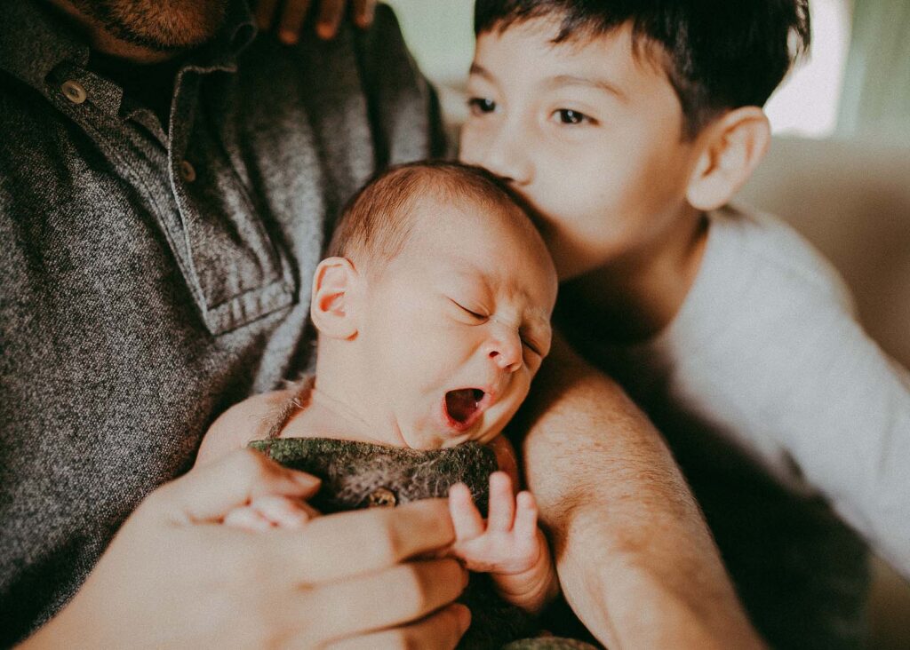 newborn baby boy yawns in daddy's arm