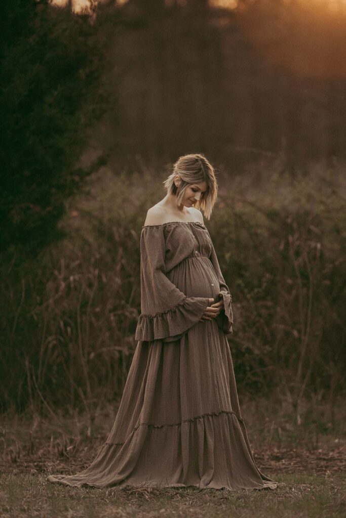 Tender and romantic pregnant woman in a maxi dress posing during her sunset maternity session in high grass at Anderson Point park. The portrait was taken by Raleigh maternity photographer - Victoria Vasilyeva Photography.