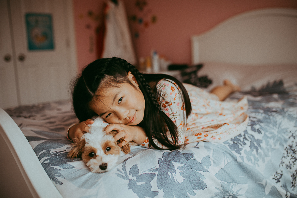 girl and puppy on a bed