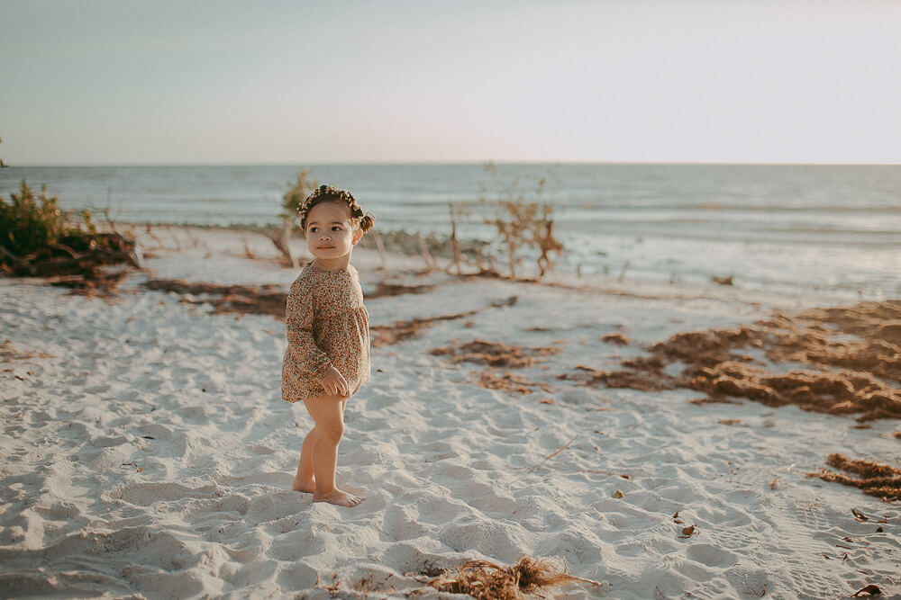baby girl on a beach wears floral romperaleigh baby storer and flower crown from Raleigh baby stores