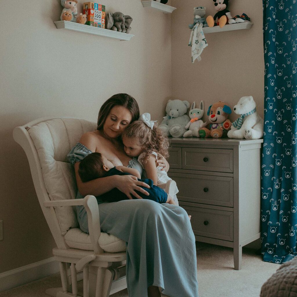 mom sitting in a rocking chair and breastfeed 10 months old son with support of lactation consultant raleigh nc
