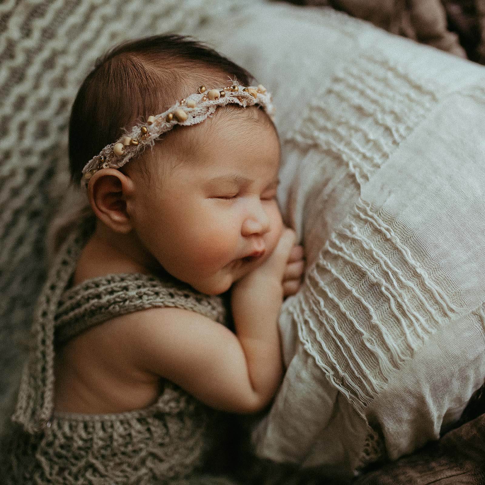 newborn baby girl sleeping on a boho styled pillow in nursary