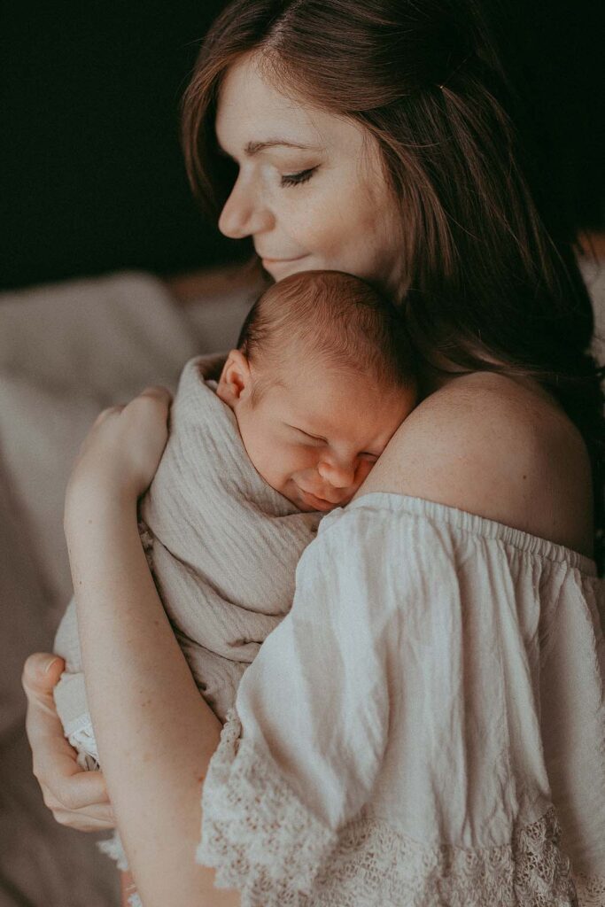 mom holds baby boy during newborn photo session near Fuquay Pediatrics