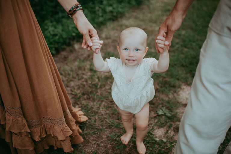 little girl holding parents arms, smile to cary family photographer and look up