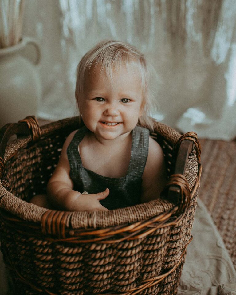 baby girl in wooven basket in photography studio near holly springs pediatrics