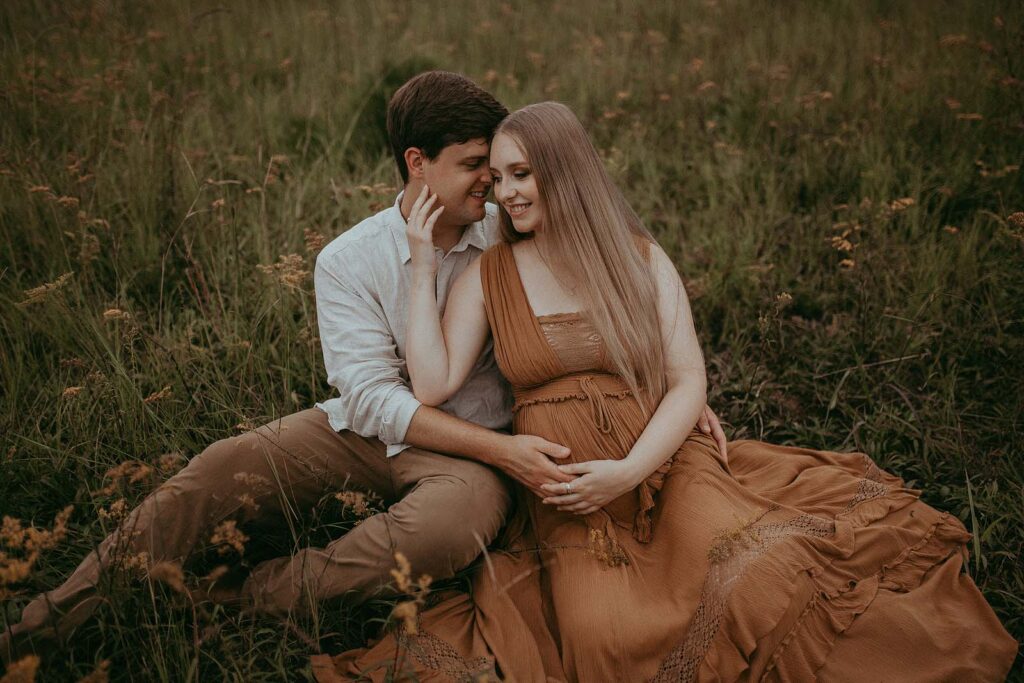 lovely mom-to-be with long blonde hair in free people maxi dresss sits among yellow flower during maternity photo session