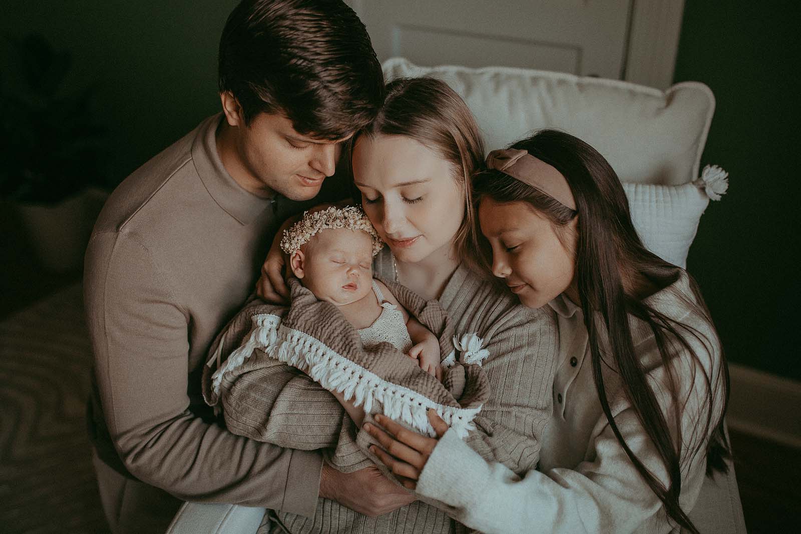 family of 4 with neaborn baby girl pose to raleigh newborn photographer at home