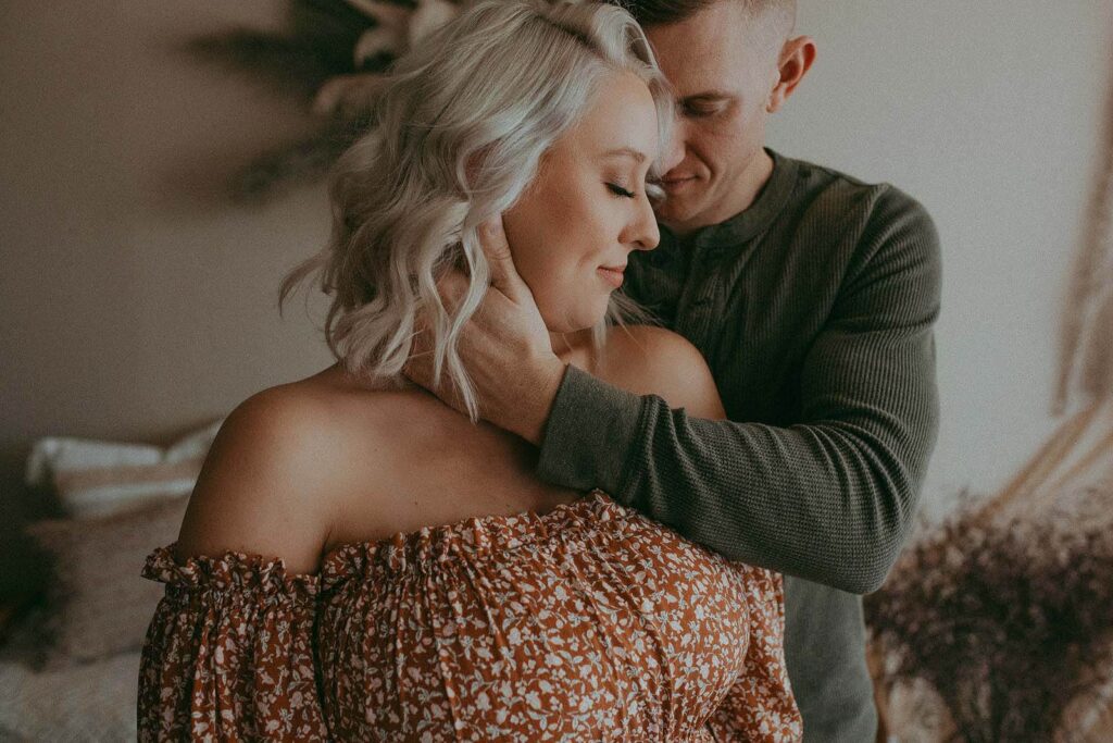 husband and wife are hugging in photography studio during maternity photo session