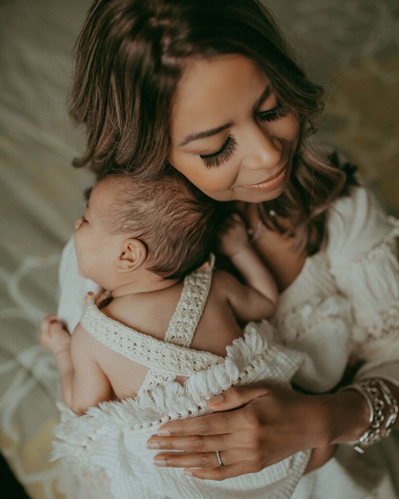 Baby boy in crochet romper sleeps and smiles on mommy's shoulder. Mom closes her eyes and lean head to the baby. Portrait was made by Victoria Vasilyeva Photography - Raleigh Family Photographer.