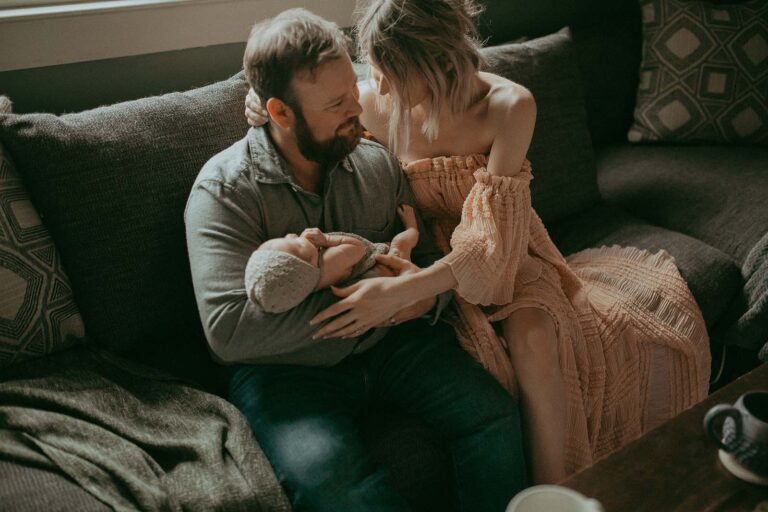 Victoria Vasilyeva Photography, a renowned newborn photographer in Chapel Hill, captures the bond between a mom with short, curly blonde hair, dad, and thier newborn baby girl in this beautiful and emotive photo session.