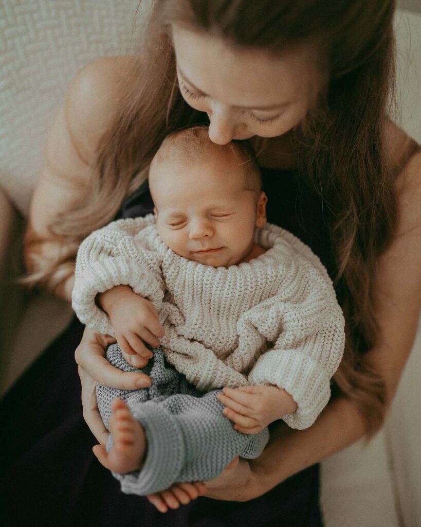 The mother with long blonde hair hugged her newborn son. This newborn portrait was taken during the newborn photo session with Victoria Vasilyeva Photography.