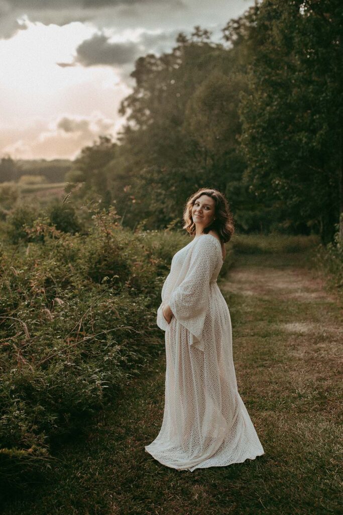 Capture the magic of pregnancy in nature with photographer, Victoria Vasilyeva near Doula Durham NC. Admire a gorgeous mom-to-be in her flowing off-white maxi dress amidst the serene backdrop of Crabtree Lake Park.