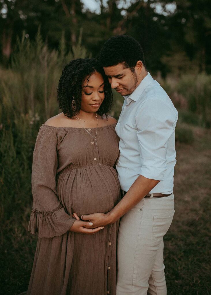 Beautiful expecting couple is posing to Cary maternity photographer - Victoria Vasilyeva Photography. Mom is wearing maxi boho dress. Dad is wearing white shirt and tan pants.