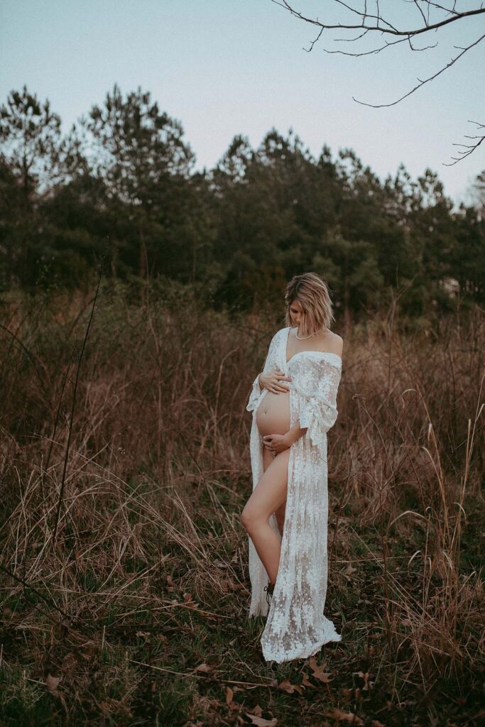 Stunning pregnant mama posing to maternity photographer near baby shower venues Greensboro NC. She has short wave hair and wears boho style maxi dress.