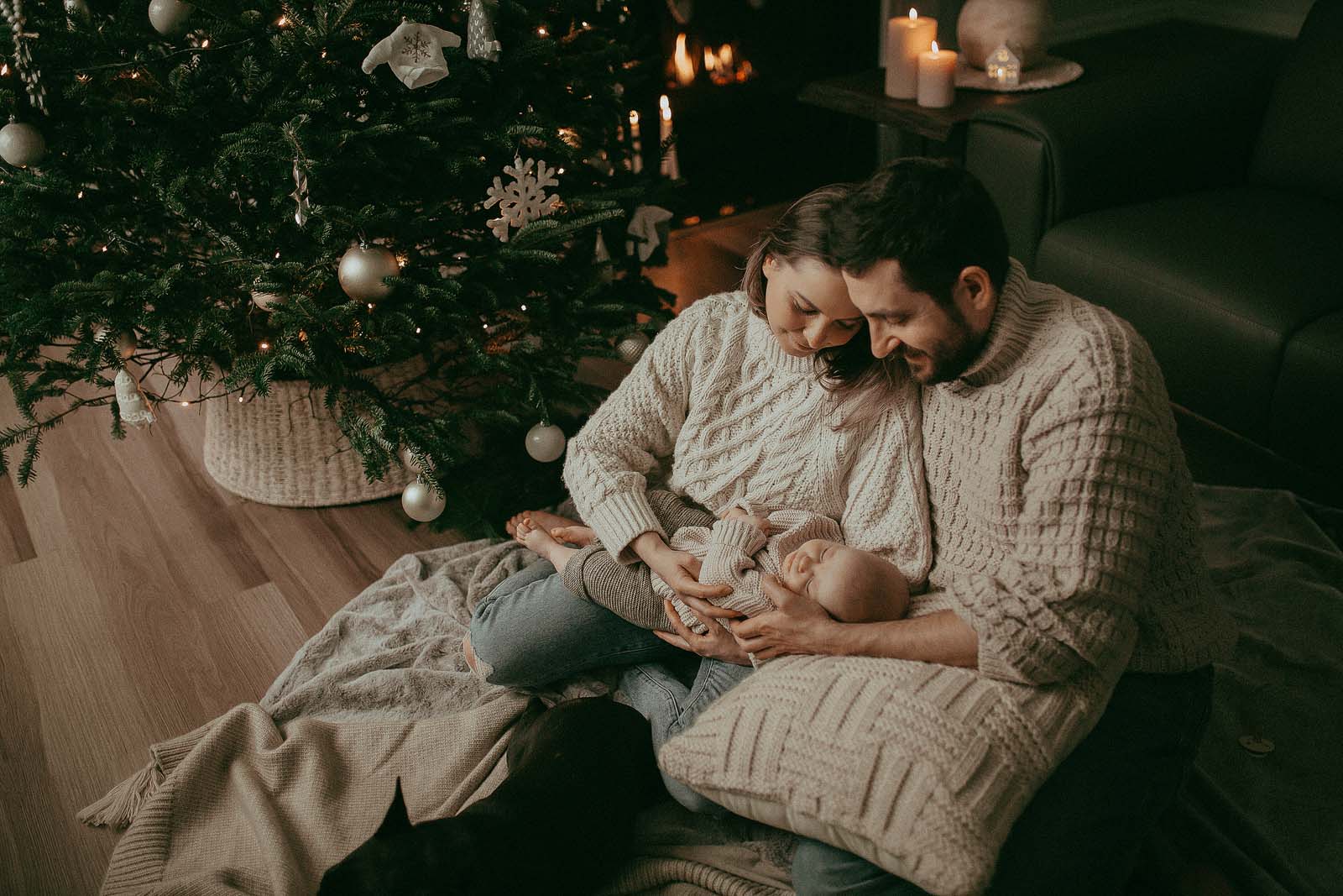 Festive family photo session. 5-month-old baby girl is sleeping under her first Christmas tree in Raleigh, NC. This family portrait was taken by Victoria Vasilyeva Photography.