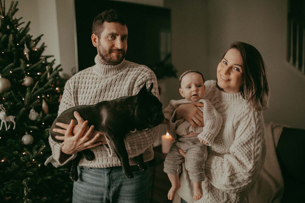 Baby girl, black French Bulldog, and family are celebrating holidays with a Christmas tree from a local farm near Raleigh, NC. Family portrait by Victoria Fasilyeva Photography.
