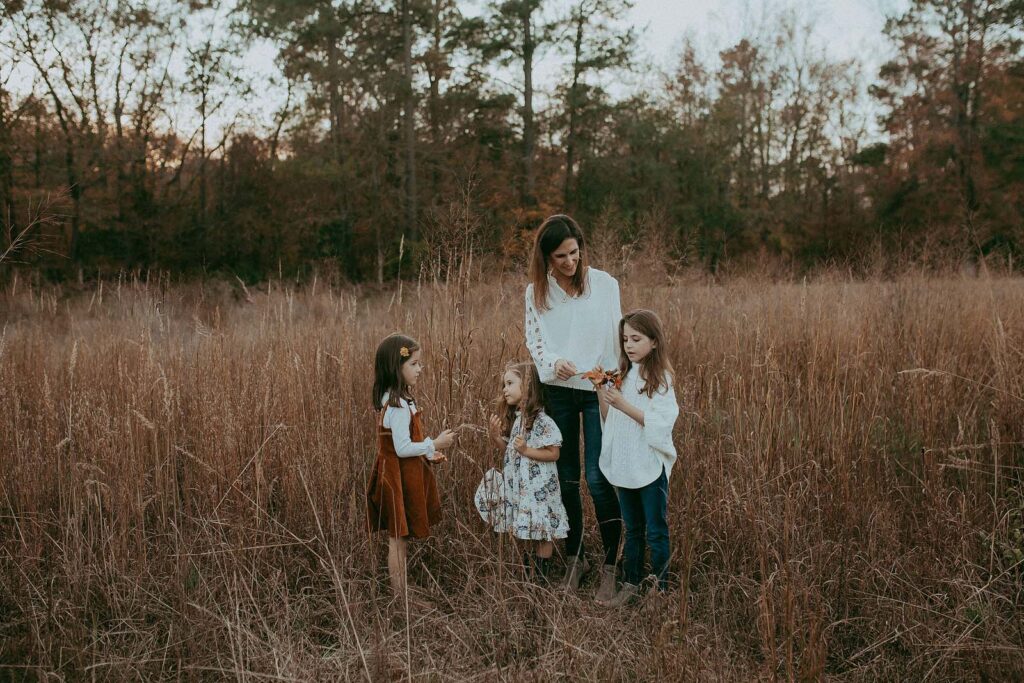 Three sisters and a mom capture their childhood memories in a photo session with Raleigh family photographer Victoria Vasilyeva Photography near a pumpkin patch.