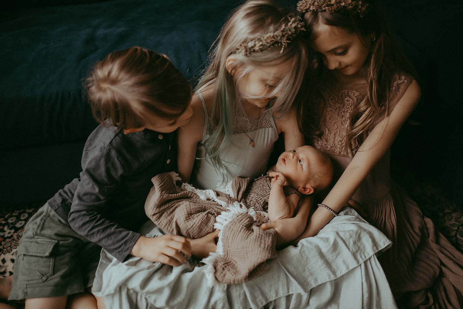 Capturing the essence of family bliss: parents and the adorable siblings, two boys and two twin girls, strike a pose in their Raleigh home during a newborn photography session.