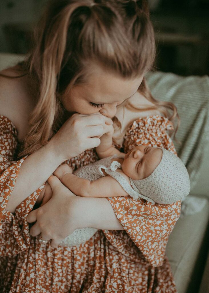 A radiant mother cradles her newborn daughter in a boho-inspired maxi dress, her gentle touch reflecting the profound love between them. Captured by Clayton Newborn Photographer - Victoria Vasilyeva Photography.