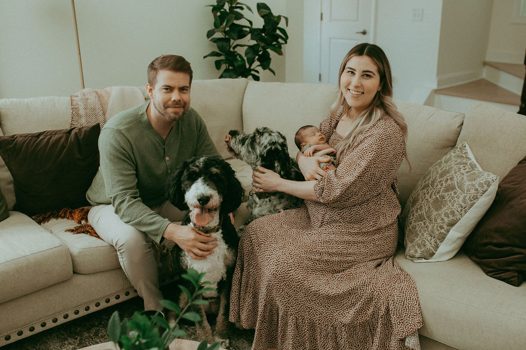 A newborn boy cradled in his parents' loving arms, their cozy boho-inspired outfits and warm smiles reflecting the joy of parenthood. Captured by Holly Springs Newborn Photographer - Victoria Vasilyeva Photography.