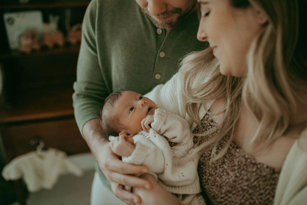 A newborn boy nestled between his parents, their faces aglow with the joy of parenthood.
