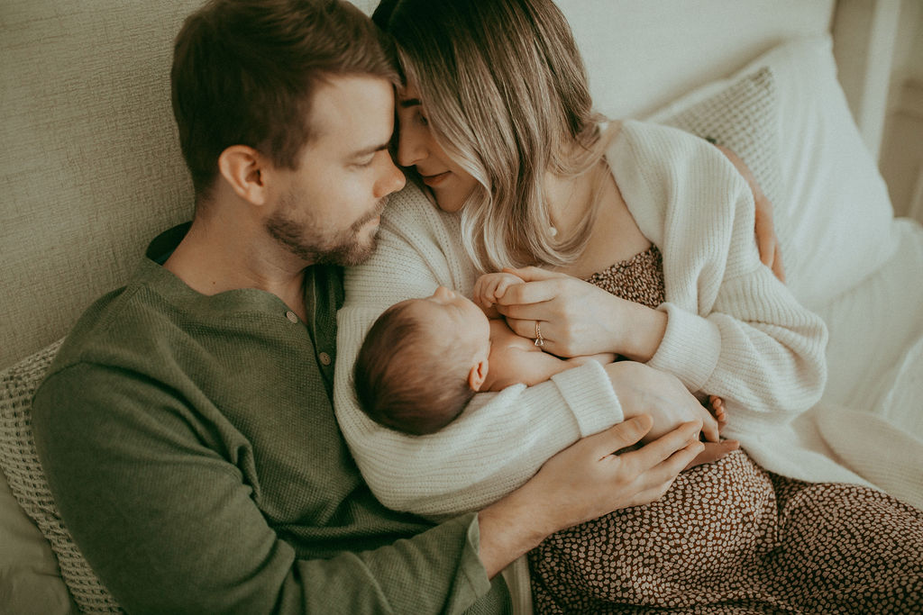 A new beginning: A newborn boy peacefully rests in his parents' arms, surrounded by the warmth of their boho-inspired home.