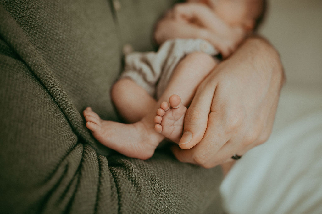 A cherished keepsake of a newborn boy's tiny hand gently grasping his father's, a testament to their unbreakable bond, captured by Holly Springs Newborn Photographer