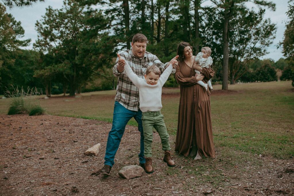 Beautiful family is playing in Lake Benson Park. They are wearing stylish outfits in earthy tones. The photo was taken near Clayton daycare by Victoria Vasilyeva Photographer.