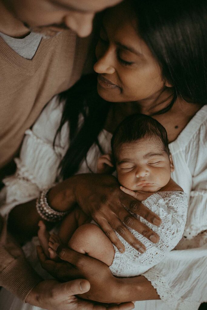 Victoria Vasilyeva Photography beautifully captures the warmth of a family of three, adorned in earthy boho outfits. Baby peacefully sleeps in mommy's arms. Mom and dad leaned to each other and enjoy the moments carrboro midwifery.