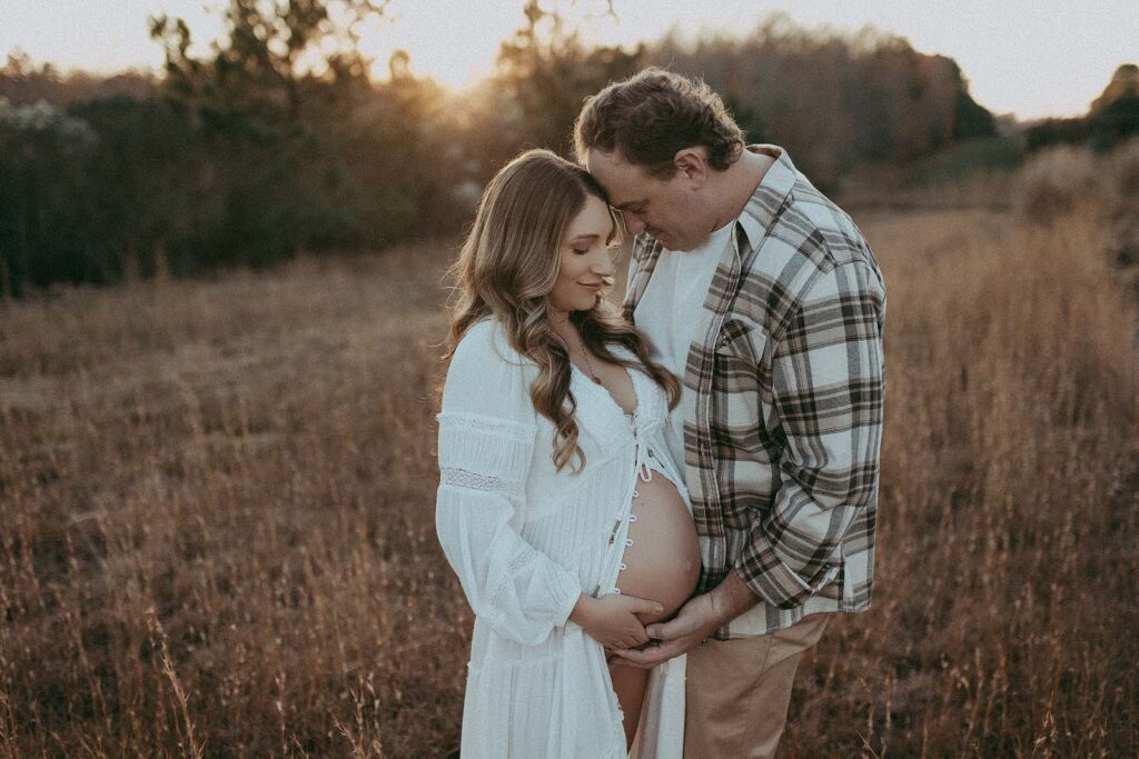 Expecting parents are posing during the maternity photo session with Victoria Vasilyeva Photography. They are wearing boho styled clothes in earthy tones.