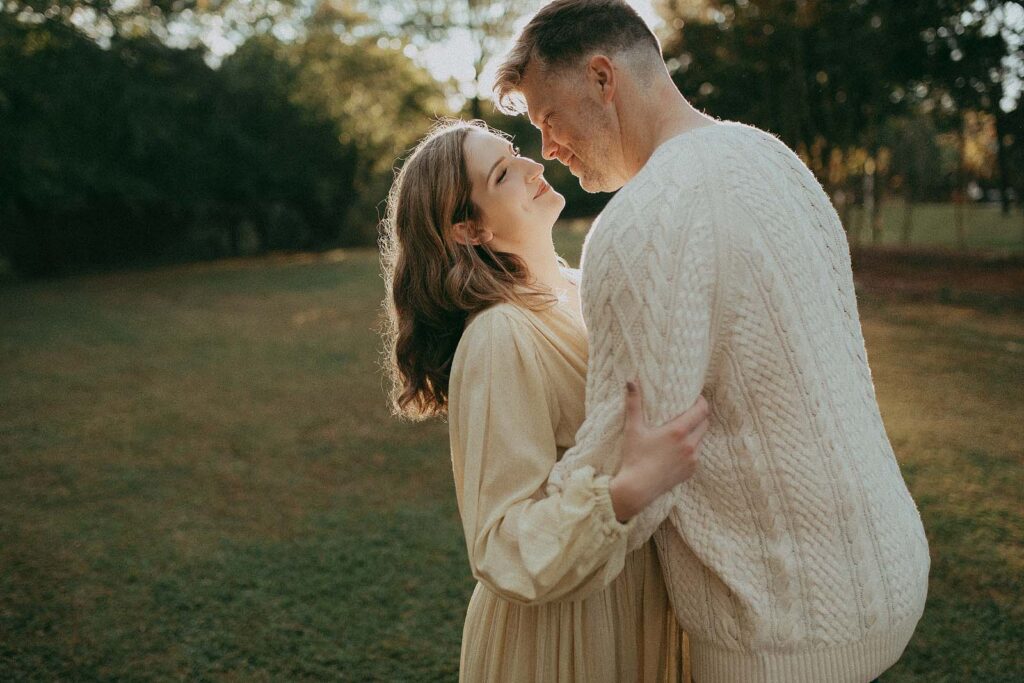 A beautiful moment captured as an expectant couple shares a warm embrace. The mother-to-be looks stunning in a flowing Free People maxi dress, while the dad-to-be exudes warmth in a stylish white knitted sweater. Their smiles radiate love and excitement for the journey ahead barefoot babies.