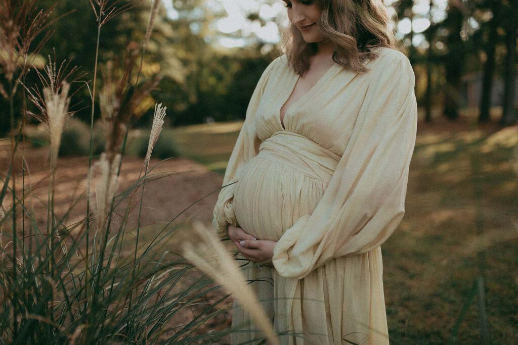 The portrait of beautiful mom-to-be in light colored boho maxi dress was taken after visiting Barefoot Babies ultrasound studio by Fayetteville maternity photographer - Victoria Vasilyeva Photography.