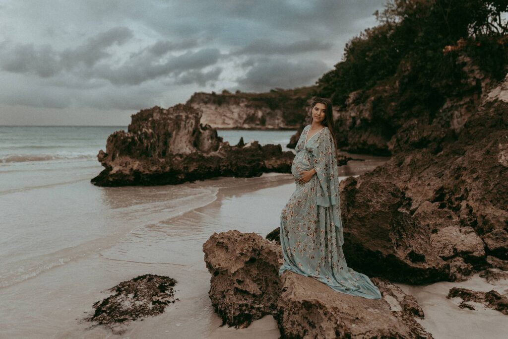 Maternity photo session with stunning mom-to-be among rocks on a beach by Victoria Vasilyeva Photography - the award-winning photographer in Wilmington, NC, specializing in newborn, maternity, and family photographs.
