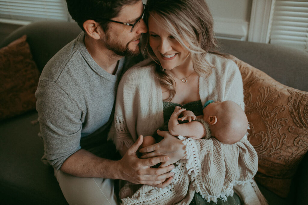The portrait of newborn baby boy with his parents. Newborn photography in Cary, NC. Victoria Vasilyeva Photography specializes in lifestyle photography, using natural light. Certified, insured, professional, safety. All outfits for baby, mom, and siblings are provided.