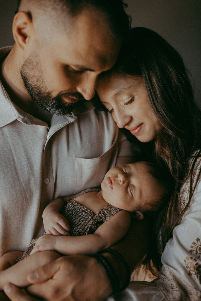 Mom and Dad cuddle their precious newborn son, Matthew, during a heartwarming in-home session by Raleigh photographer Victoria Vasilyeva.