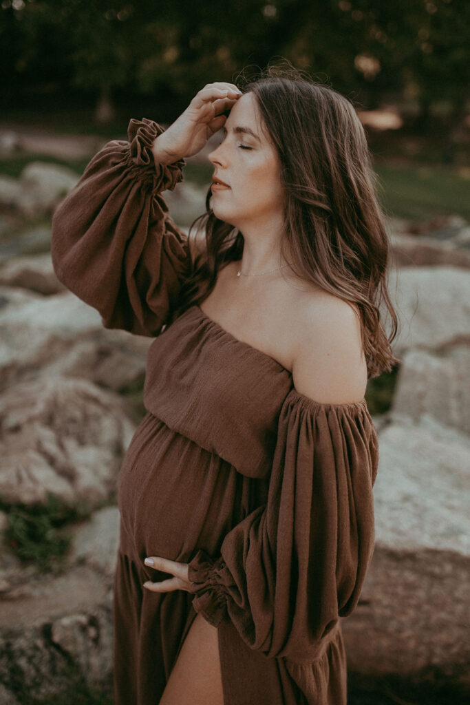 A gentle portrait of the mom-to-be, wearing a brown maxi dress.