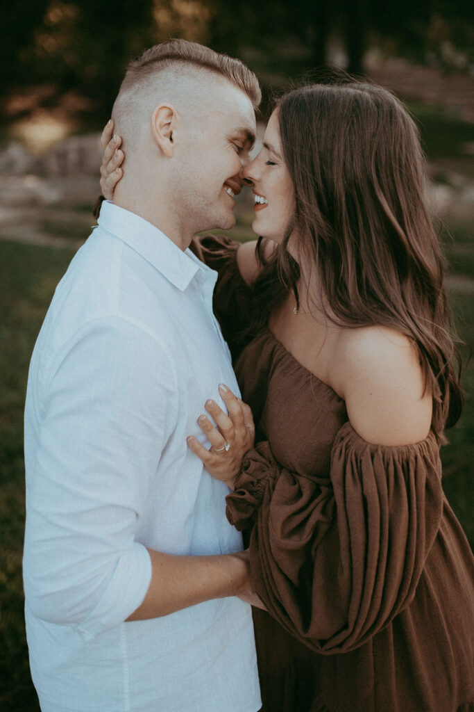 Candid moment of the expecting couple laughing and enjoying each other's company during maternity photo session at NCMA, with the mom-to-be in a brown maxi dress.