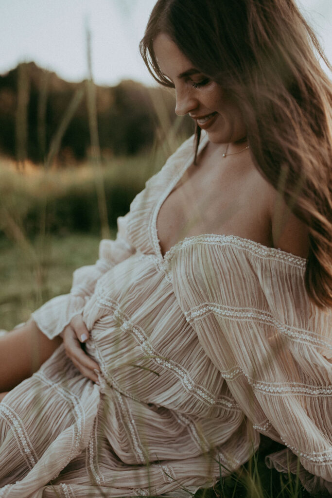 Close-up of the expecting mother’s smiling face as she looks down at her belly. Maternity photo session at NCMA in Raleigh, NC