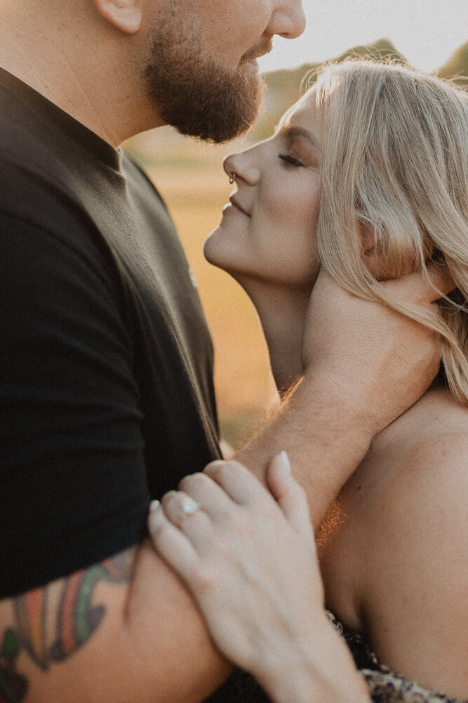 Intimate close-up of an expecting couple embracing in soft evening light during a maternity session. Photo by Victoria Vasilyeva Photography.