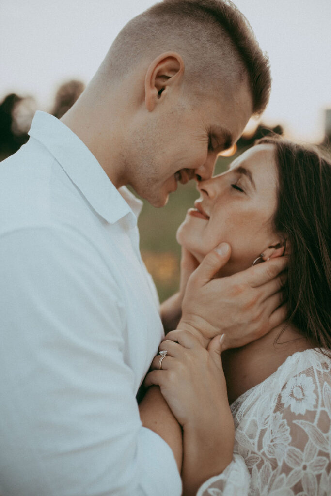 Close-up intimate moment of a couple touching foreheads and smiling with eyes closed, capturing emotional connection during their maternity photo session at NCMA in Raleigh, NC.