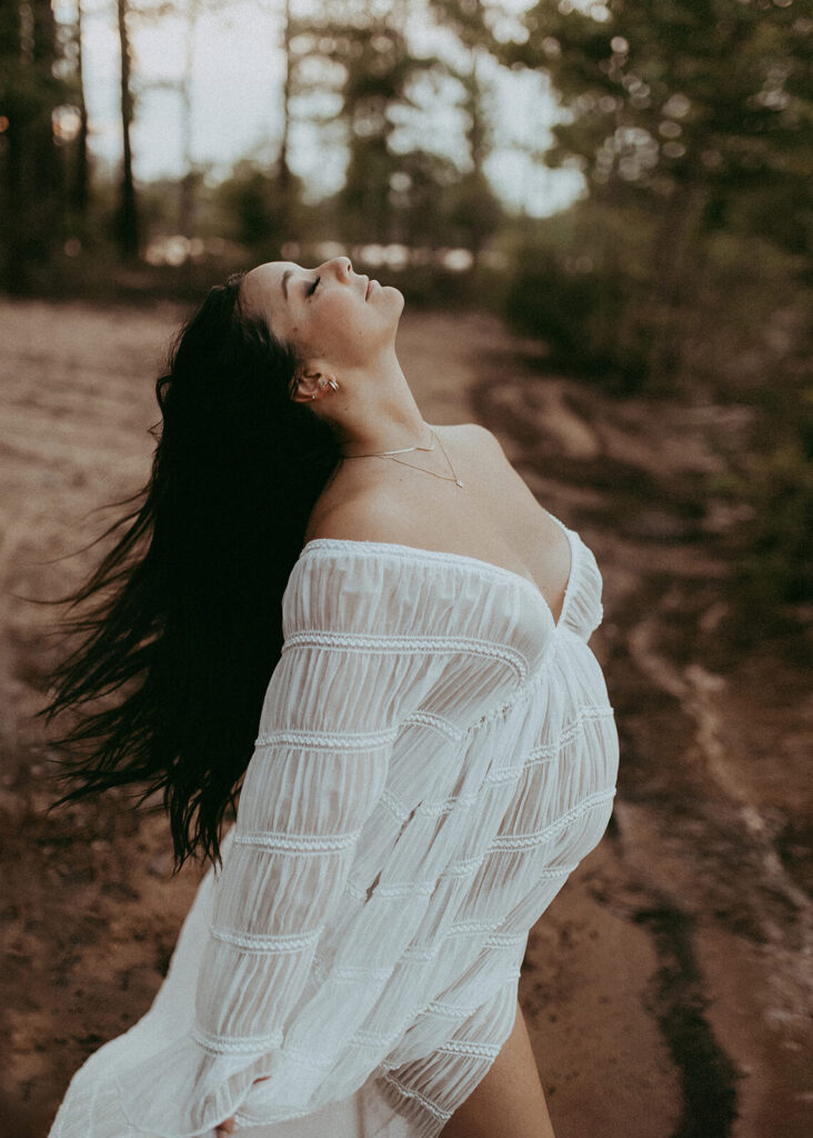 Pregnant woman arching her back and lifting her face toward the sky in a flowing white gown, expressive maternity photography Cary NC by Victoria Vasilyeva Photography.