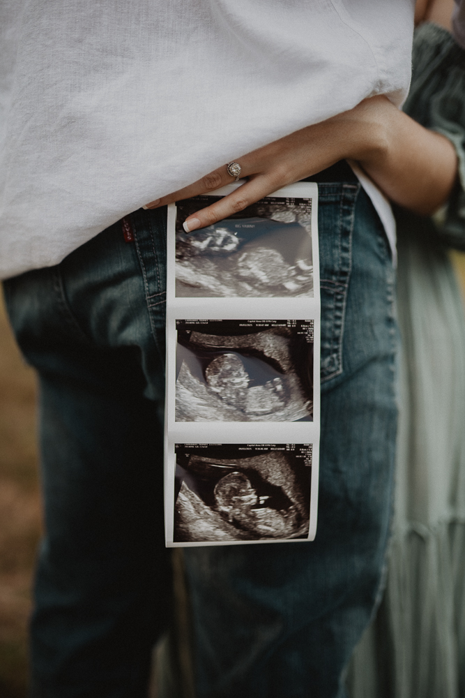 Pregnancy ultrasound photos held during outdoor maternity session, symbolizing the journey with a Raleigh Fertility Clinic. Captured by Raleigh photographer Victoria Vasilyeva Photography.