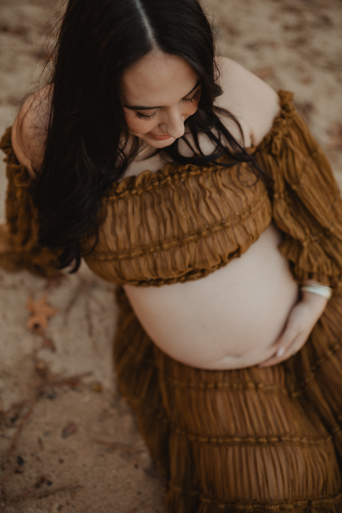 Close-up maternity portrait of a pregnant woman wearing a brown textured two-piece maternity outfit with an off-the-shoulder top and flowing skirt during an outdoor session in Greensboro, NC with Greensboro maternity photographer.