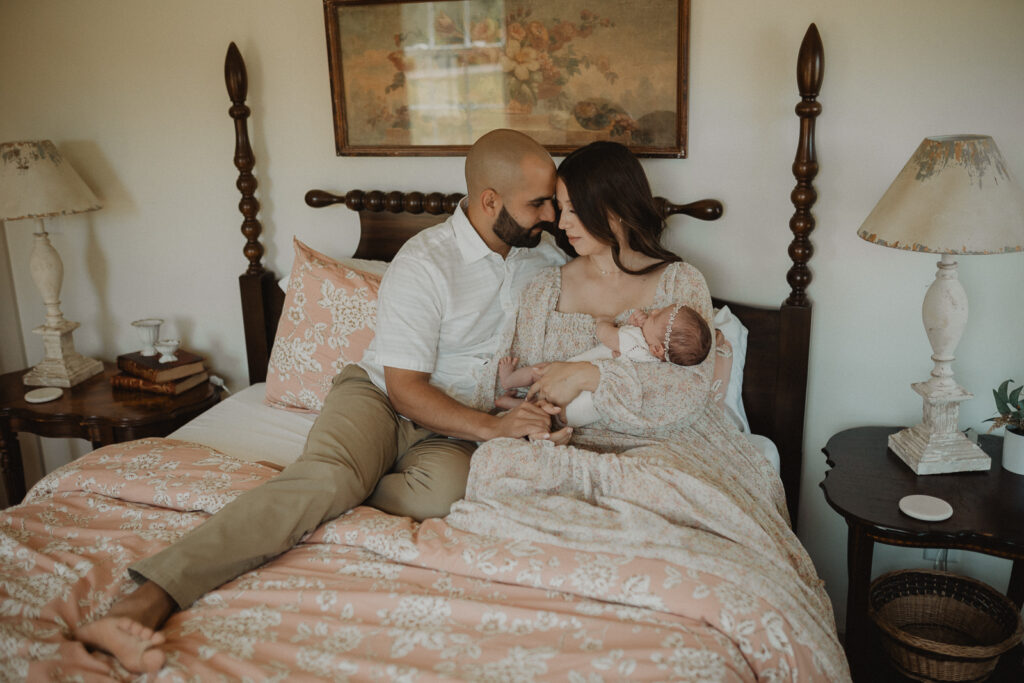 Parents admiring their sleeping newborn daughter during an intimate in-home newborn photography session in Cary, NC.