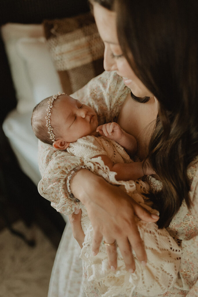 Mother holding her newborn daughter during an in-home session celebrating the early weeks of motherhood and breastfeeding.