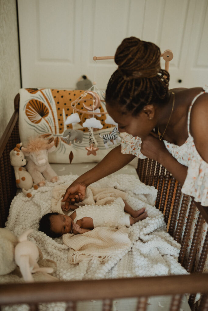 A loving mother leans over the crib to comfort her baby boy in a thoughtfully designed nursery during a lifestyle newborn session captured by Raleigh newborn photographer - Victoria Vasilyeva Photography. Goodnight Sweet Baby