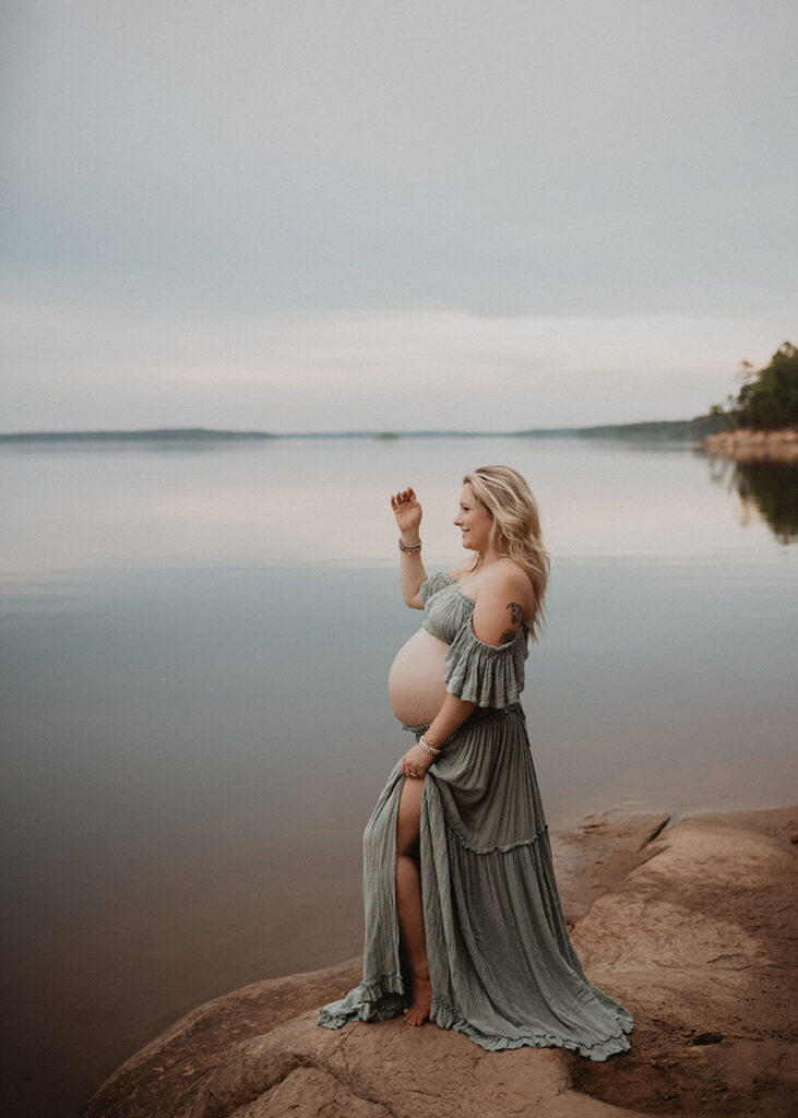 Elegant maternity portrait of a pregnant mother in a flowing sage green dress by a Wake Forest photographer.