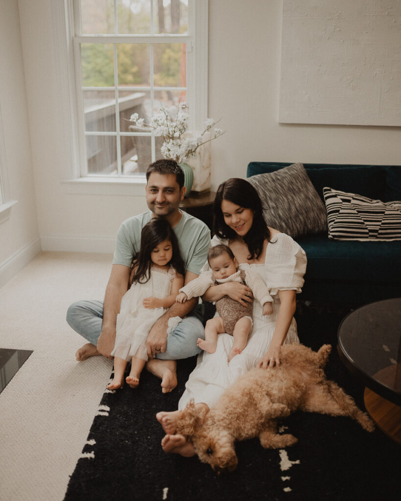 Family of four with their dog gathered in a bright living room during an in-home family photo session by Victoria Vasilyeva Photography, a Chapel Hill family photographer.