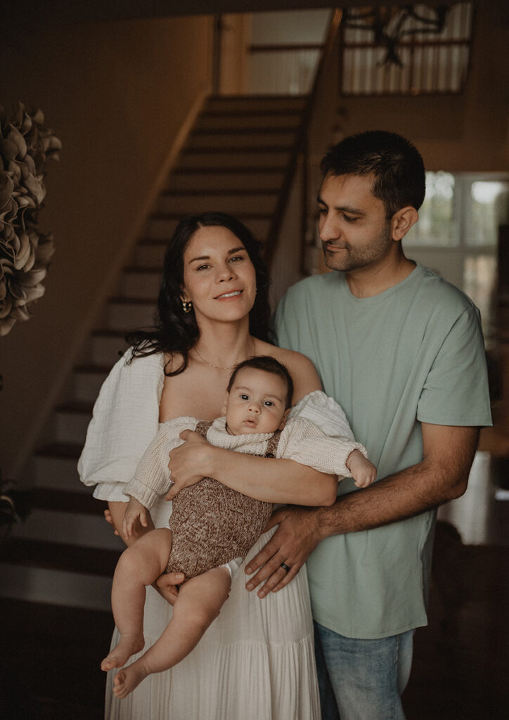 In-home family photography in Chapel Hill by Victoria Vasilyeva Photography, featuring parents cuddling their baby boy and capturing genuine connection in natural light.