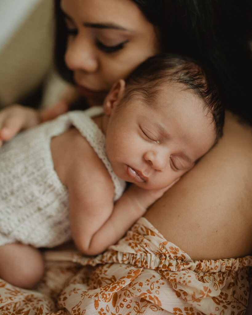 Close-up of a sleeping newborn resting on mother's shoulder during a natural in-home newborn session with Victoria Vasilyeva Photography.